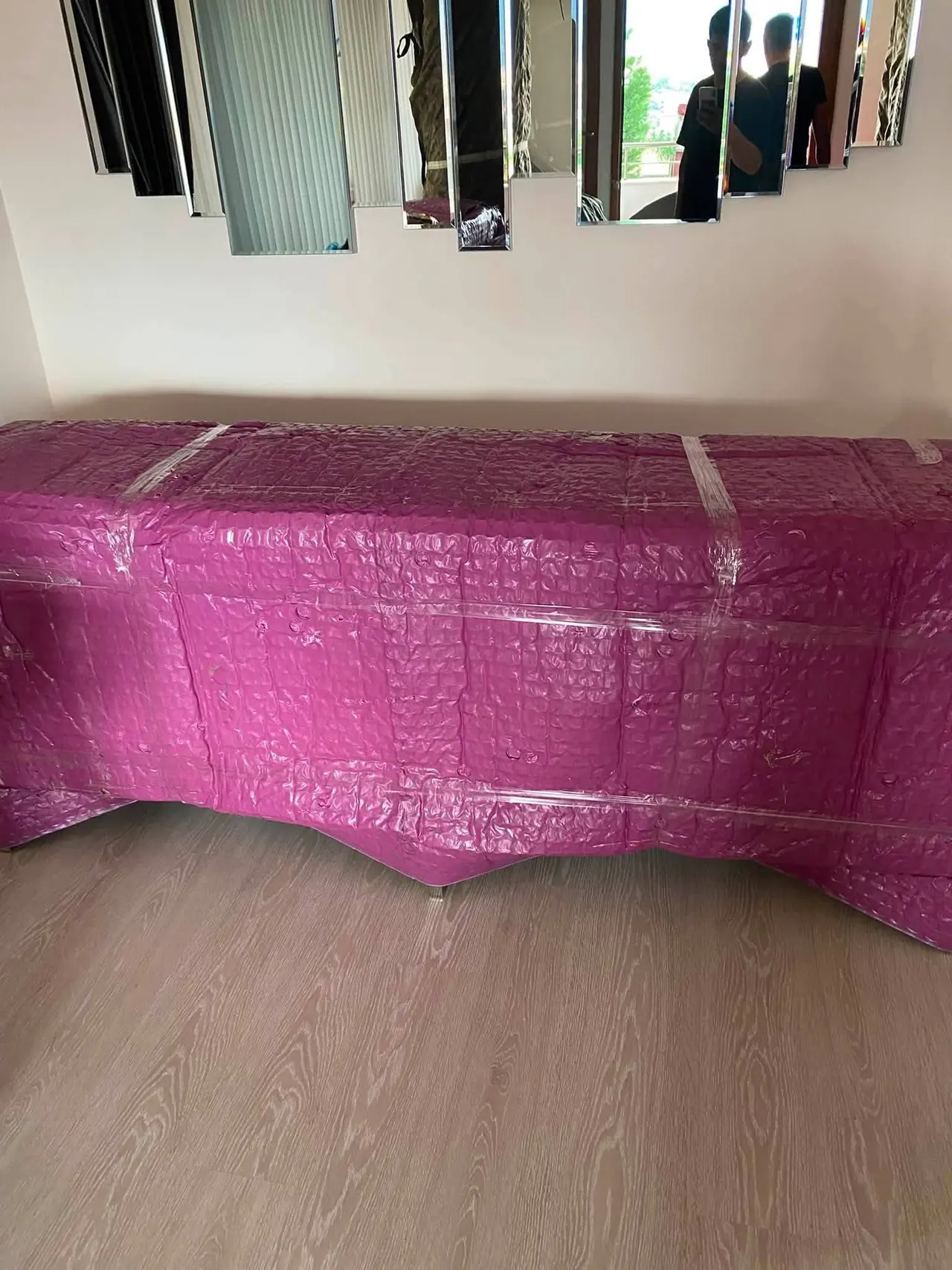 Ayna panolu duvarın önünde balonlu naylon ve streç bantla tamamen sarılmış konsol
